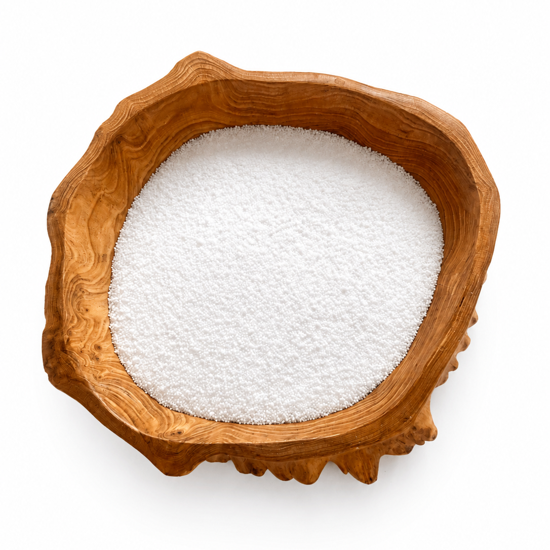 A rustic, irregularly shaped wooden bowl filled with white sugar, photographed from directly above on a clean white background.