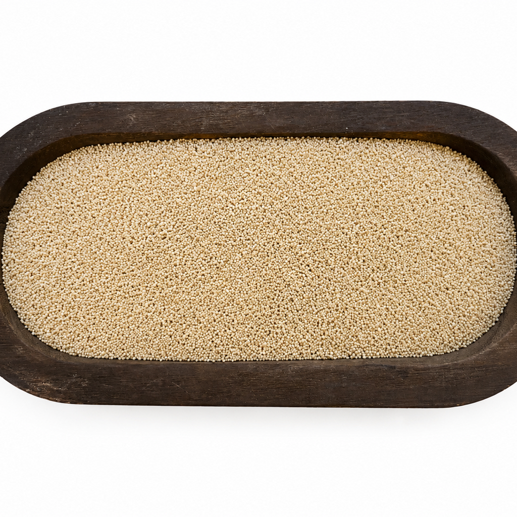 A top-down view of beige grains or seeds contained within an oval dark brown wooden tray, isolated on a white background.