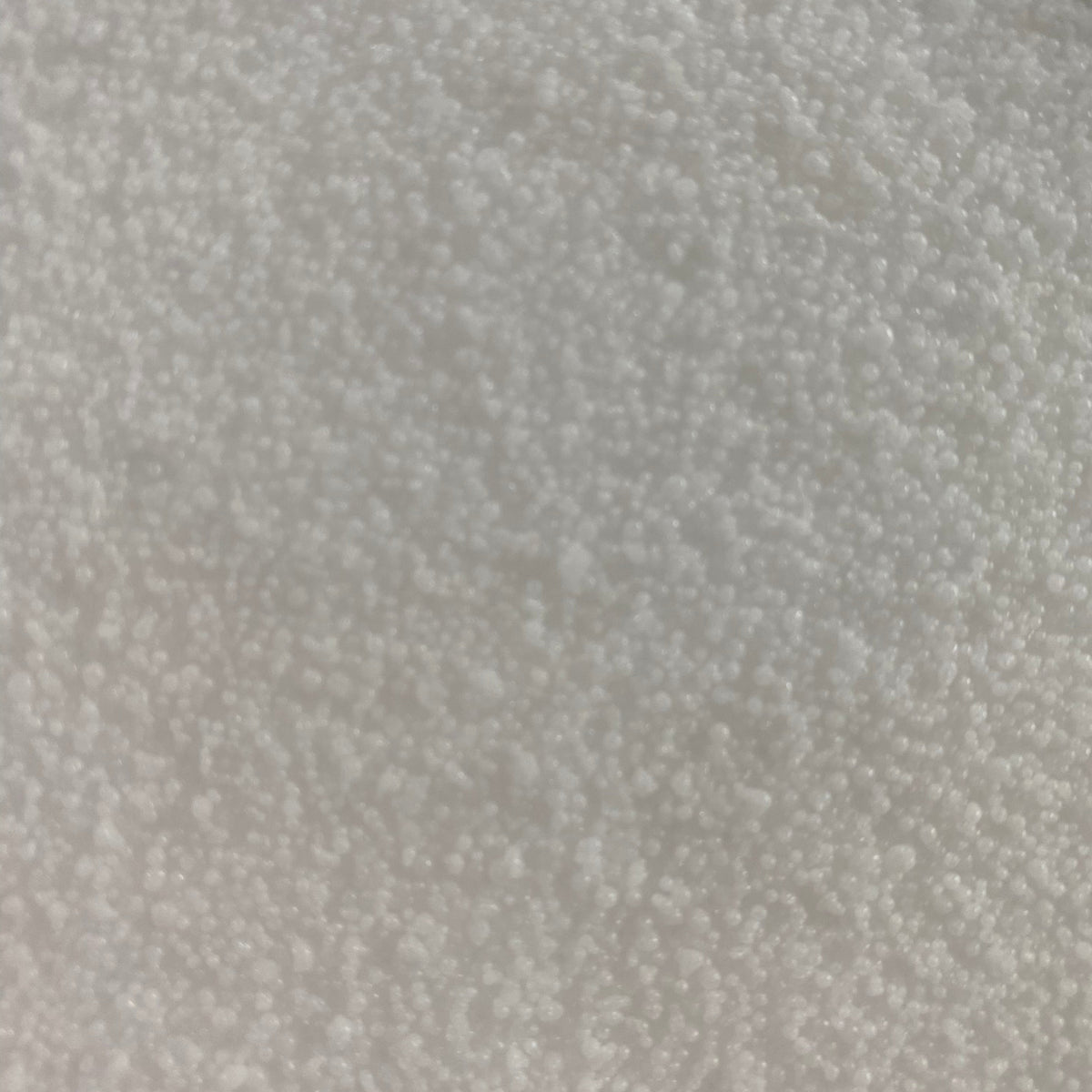A close-up texture shot of white micro plastic beads or pellets filling the entire frame.