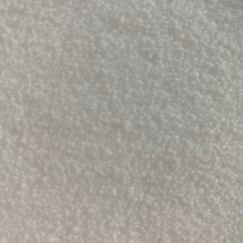 A close-up texture shot of white micro plastic beads or pellets filling the entire frame.